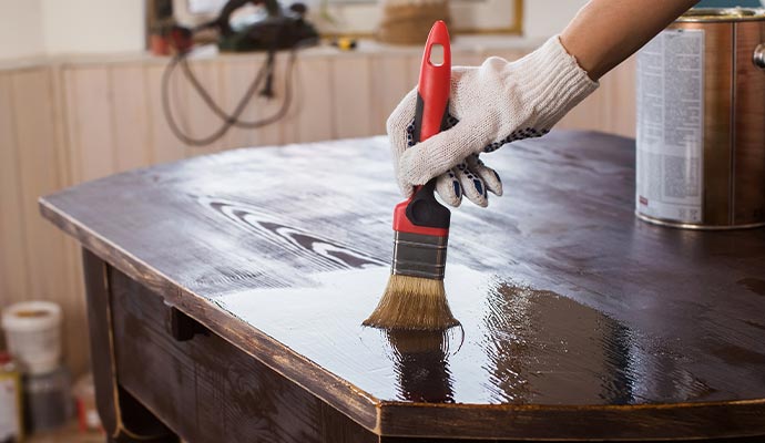 Person applying a finish to a wooden table