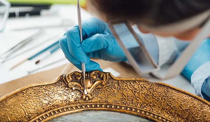 Person cleaning an ornate frame with equipment