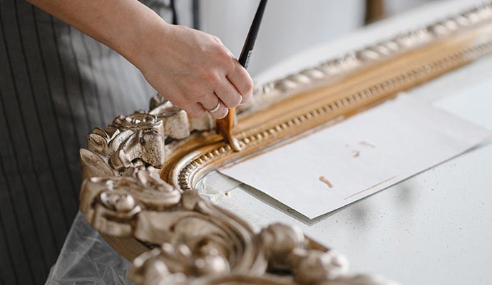 A person restoring an ornate frame