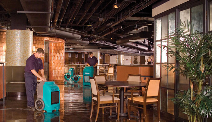 professional workers using dehumidifier to dry up a flooded restaurant